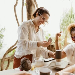 Happy friends enjoying a pottery class outdoors, fostering creativity and togetherness.