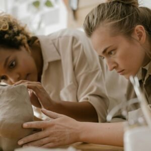Two women focusing on crafting a clay sculpture in a ceramic workshop.