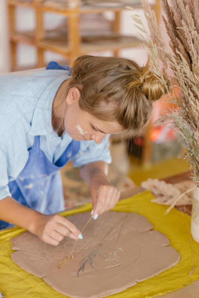 Focused woman creating handmade clay art with natural materials indoors.