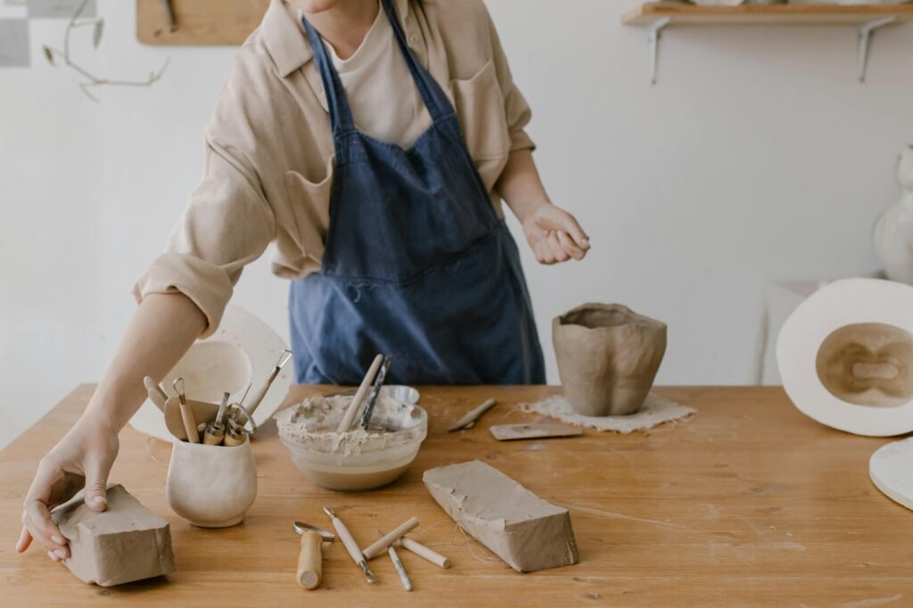 Co-working erdvė A woman working on pottery in a workshop, showcasing artisan tools and clay.
