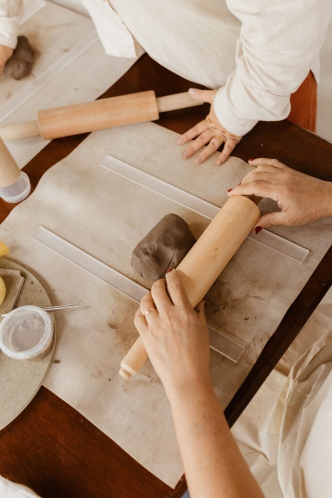 Two people crafting clay with rolling pins, showcasing art skills.