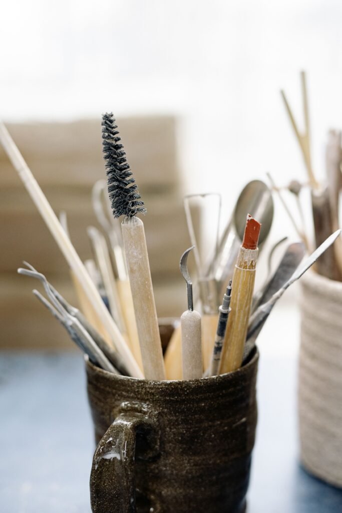A collection of assorted art tools in a ceramic mug, ideal for creative projects.