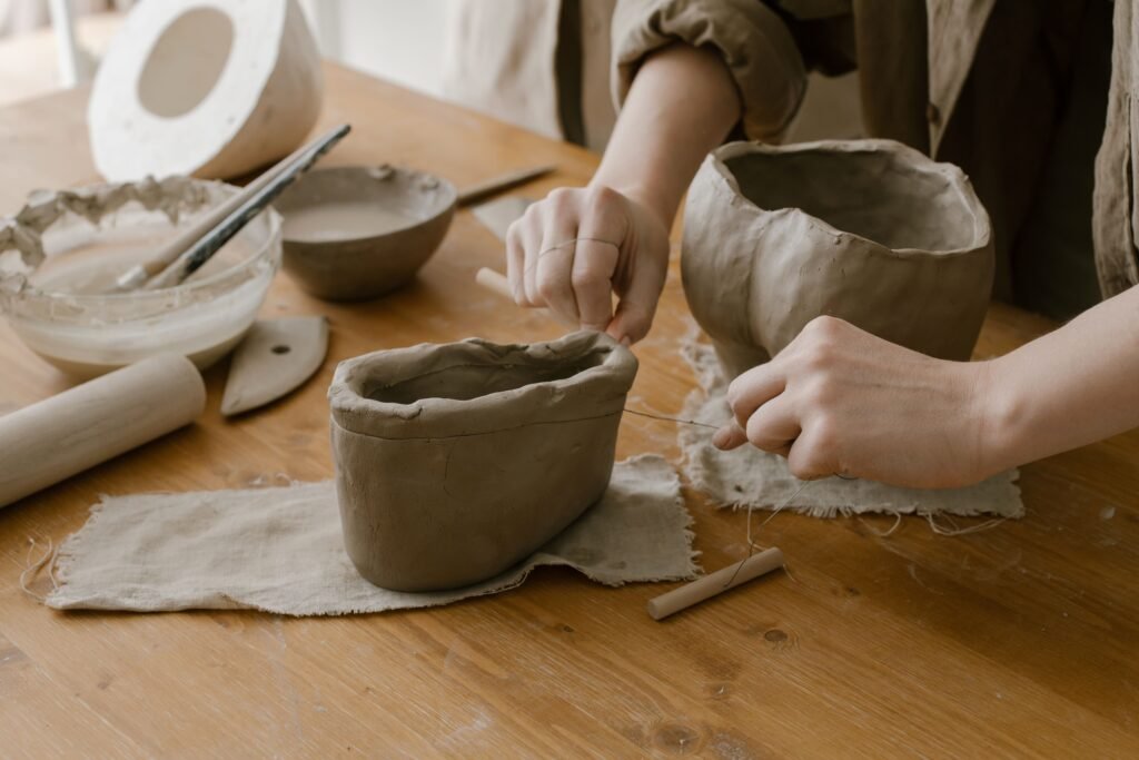 Hands shaping clay into pottery in a serene indoor setting, highlighting artisanal skill.