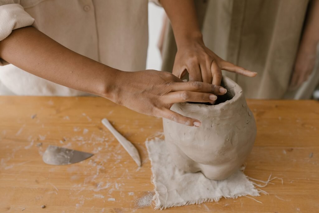 Close-up view of hands molding a clay pot, showcasing pottery techniques and craftsmanship.