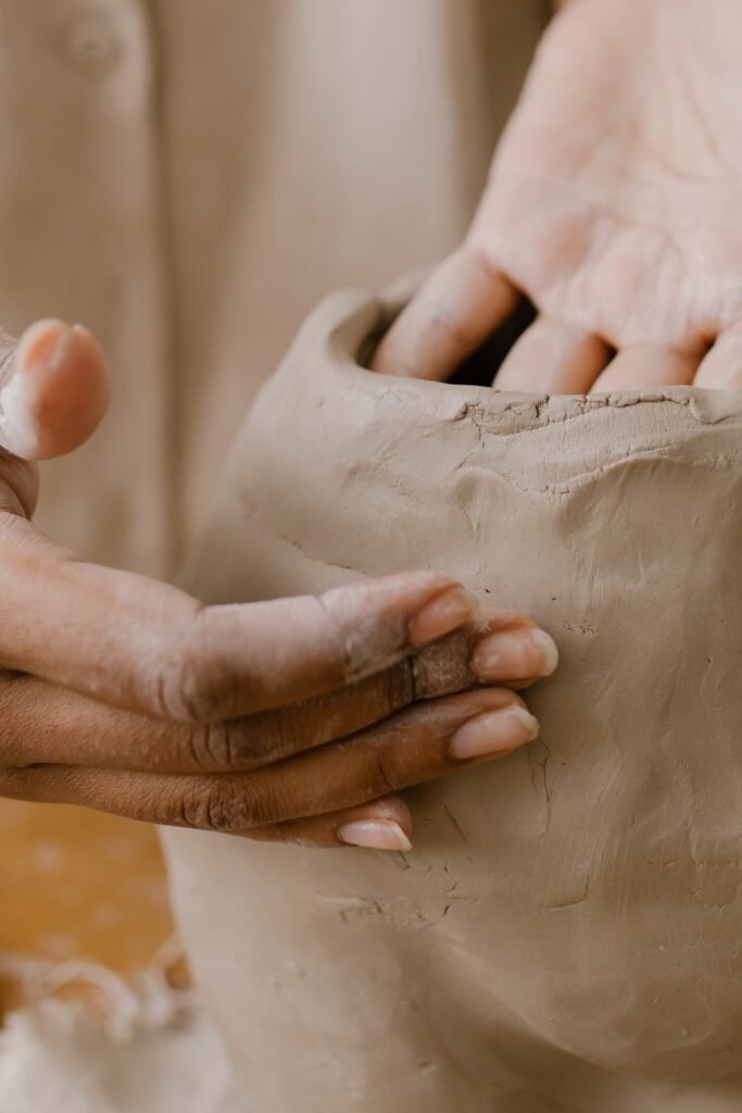 Artisan hands sculpting a clay pot in a detailed close-up in a pottery workshop.