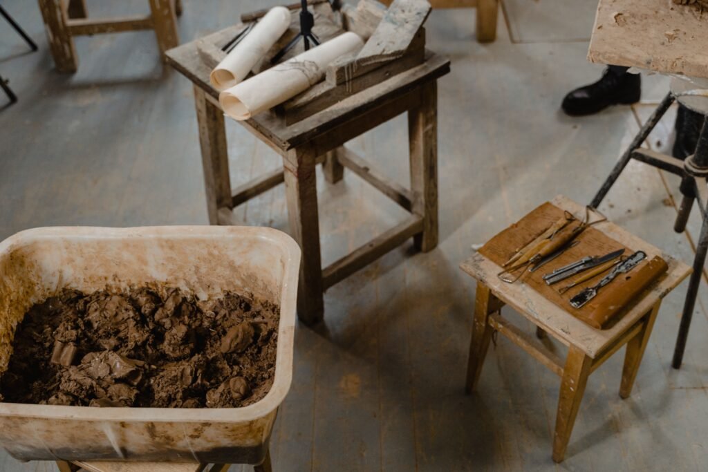 Overhead view of a craft studio with clay, tools, and wooden tables, ideal for creative projects.